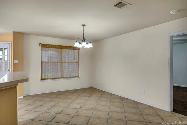 an empty room with chandelier fan and windows