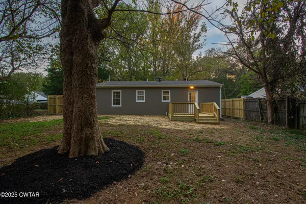 a view of a house with backyard and a tree