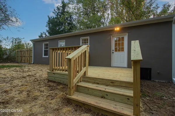 a view of backyard with wooden fence and large trees