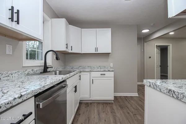 a kitchen with granite countertop white cabinets and white appliances