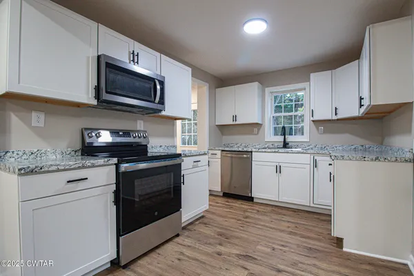 a kitchen with granite countertop white cabinets and white appliances