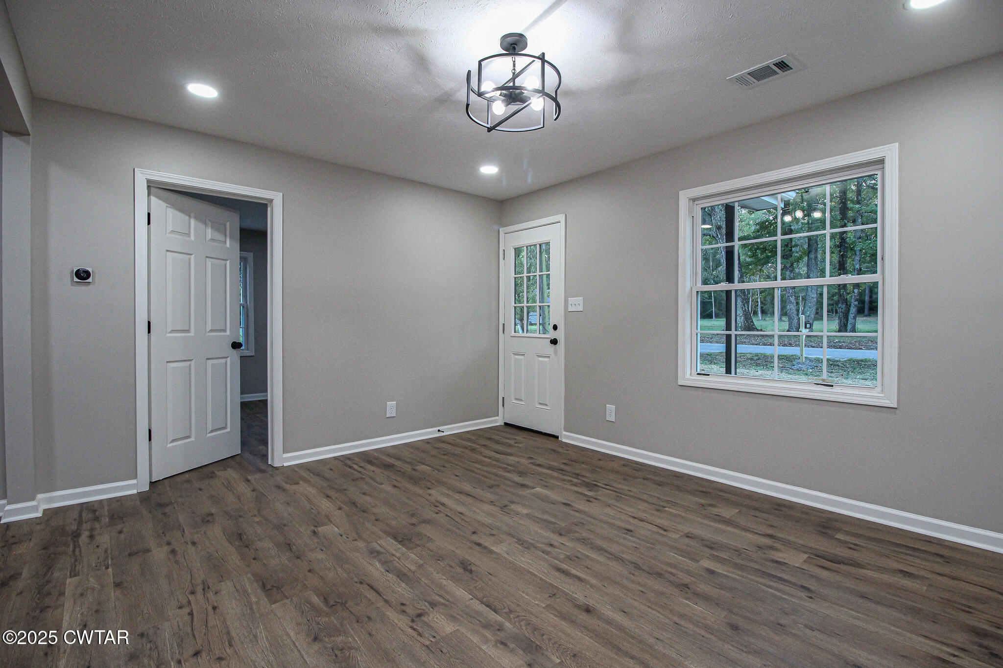 107 Lower Brownsville Road Jackson, TN 38301 - Photo 7 of 17 an empty room with wooden floor chandelier and windows