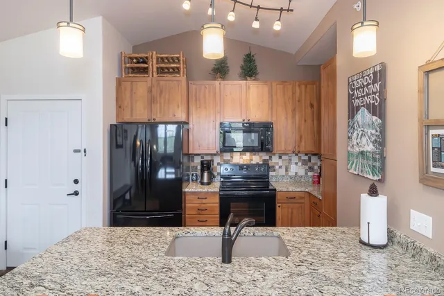 a kitchen with stainless steel appliances kitchen island granite countertop a refrigerator and a sink