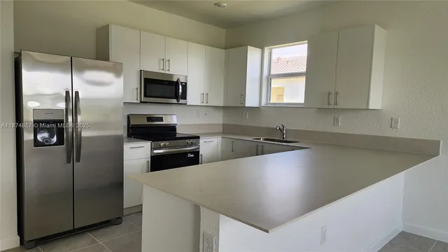 a kitchen with stainless steel appliances a refrigerator a sink a stove a microwave and island