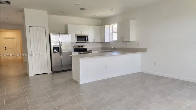 a kitchen with stainless steel appliances a sink a stove a microwave a refrigerator a window