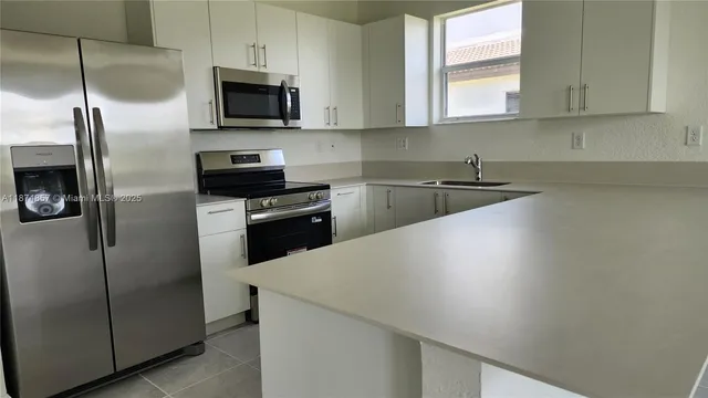 a kitchen with a refrigerator a microwave a sink and cabinets