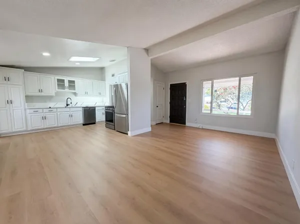a view of empty room with wooden floor and window