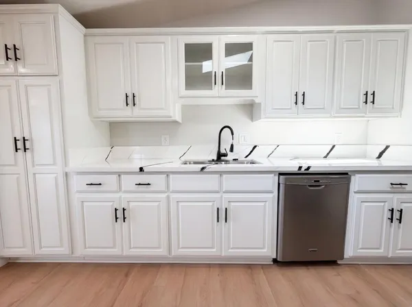 a kitchen with white cabinets and sink