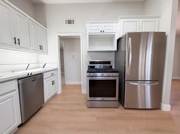 a kitchen with a refrigerator sink and white cabinets