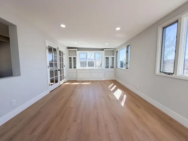 a view of empty room with wooden floor and fan