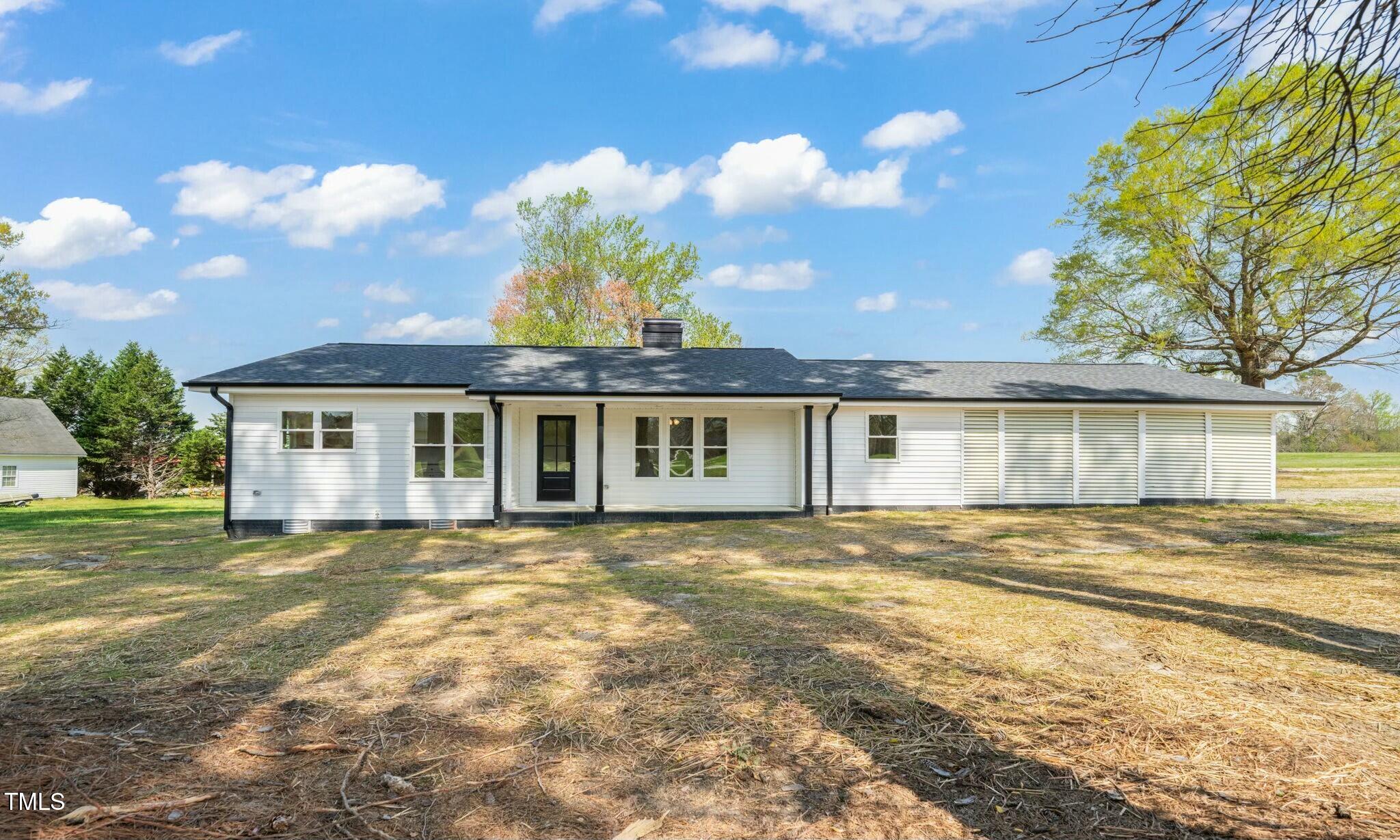 a view of a house next to a big yard and large trees
