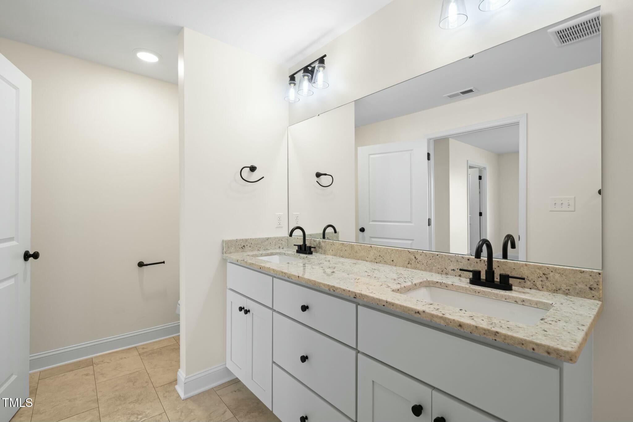 8917 Fowler Road Zebulon, NC 27597 - Photo 12 of 33 a bathroom with a granite countertop sink and a mirror