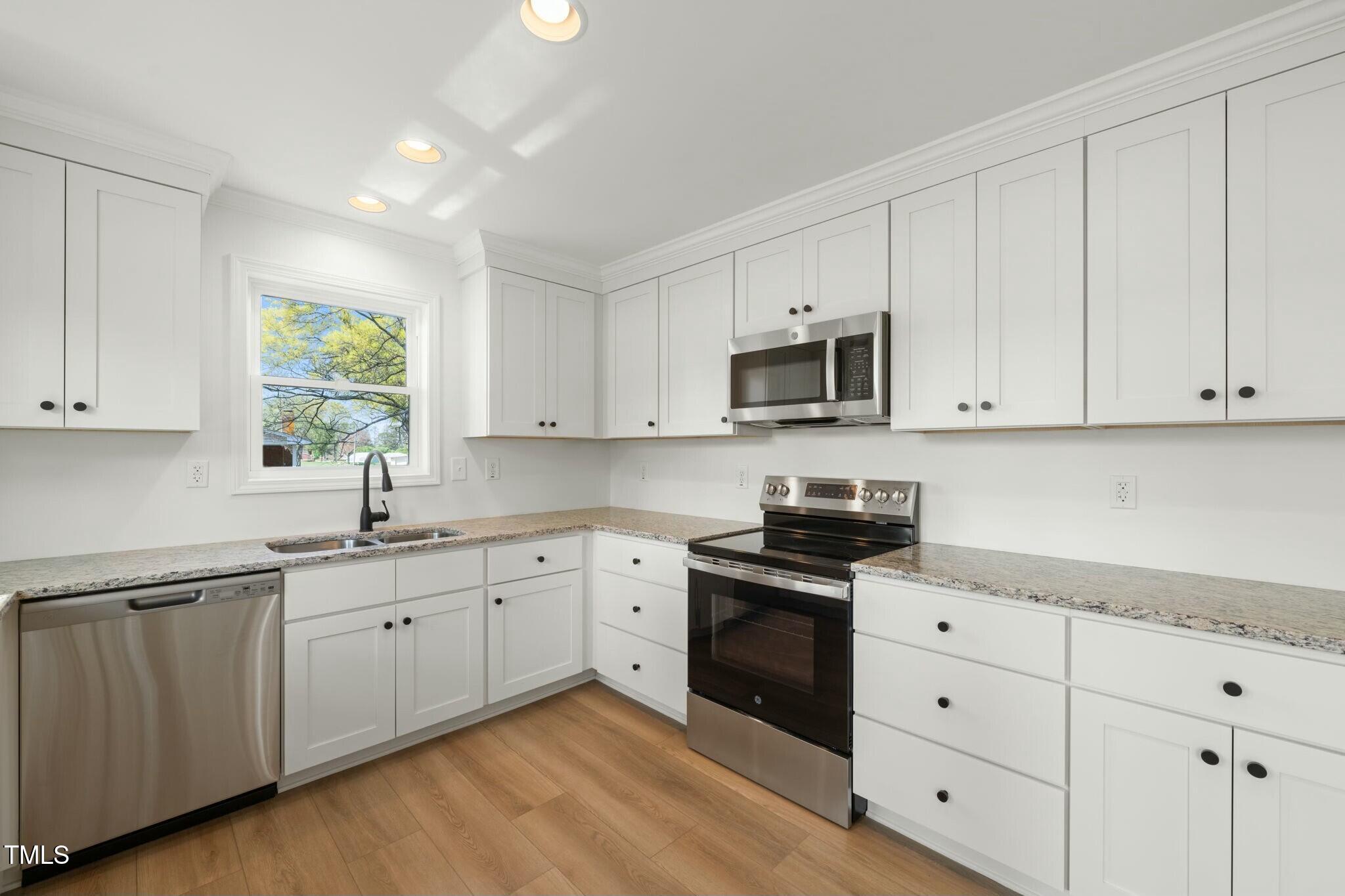 8917 Fowler Road Zebulon, NC 27597 - Photo 20 of 33 a kitchen with white cabinets sink and window