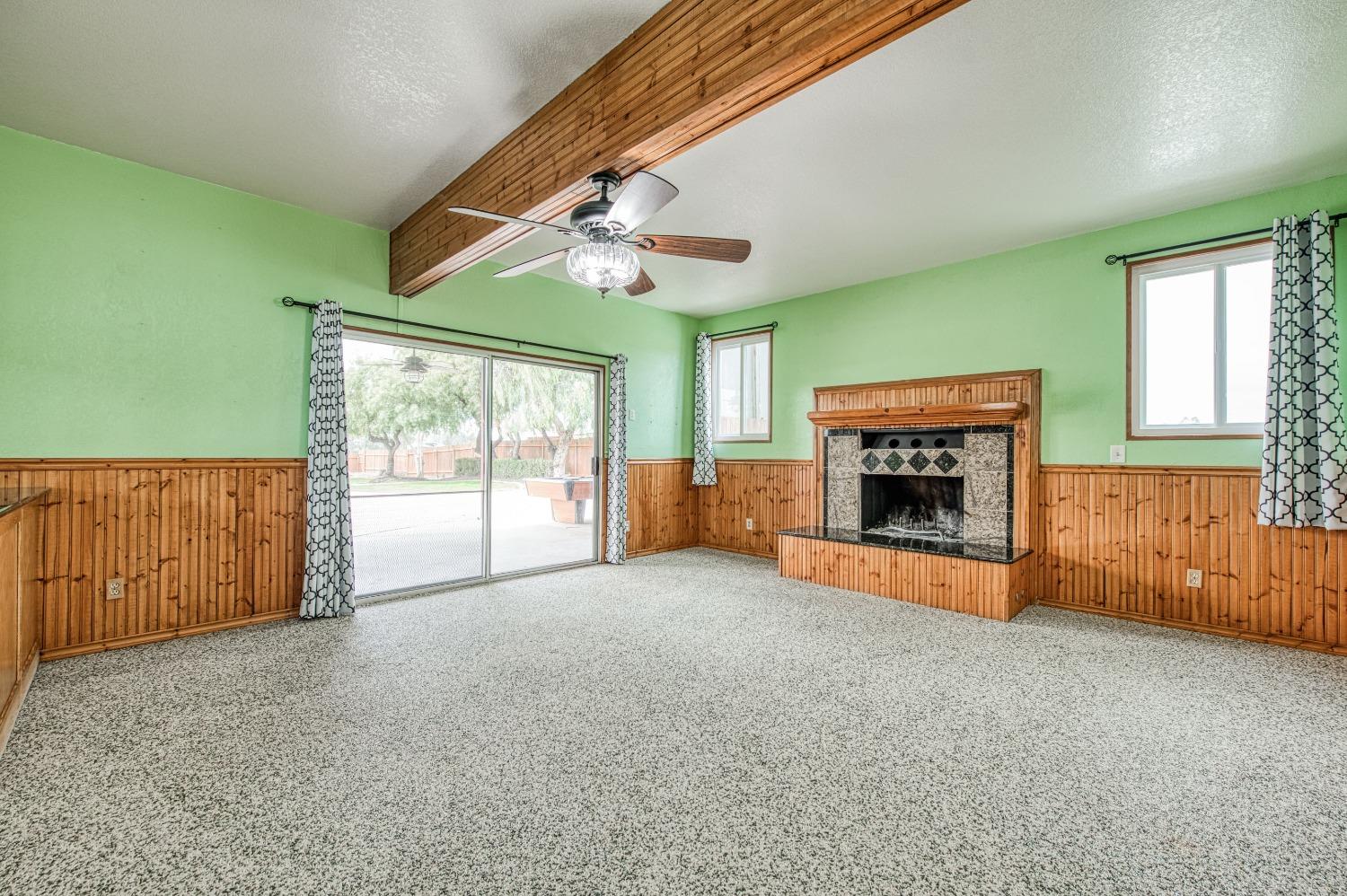 31334 Donald Avenue Madera, CA 93636 - Photo 14 of 38 an empty room with windows fireplace and a ceiling fan