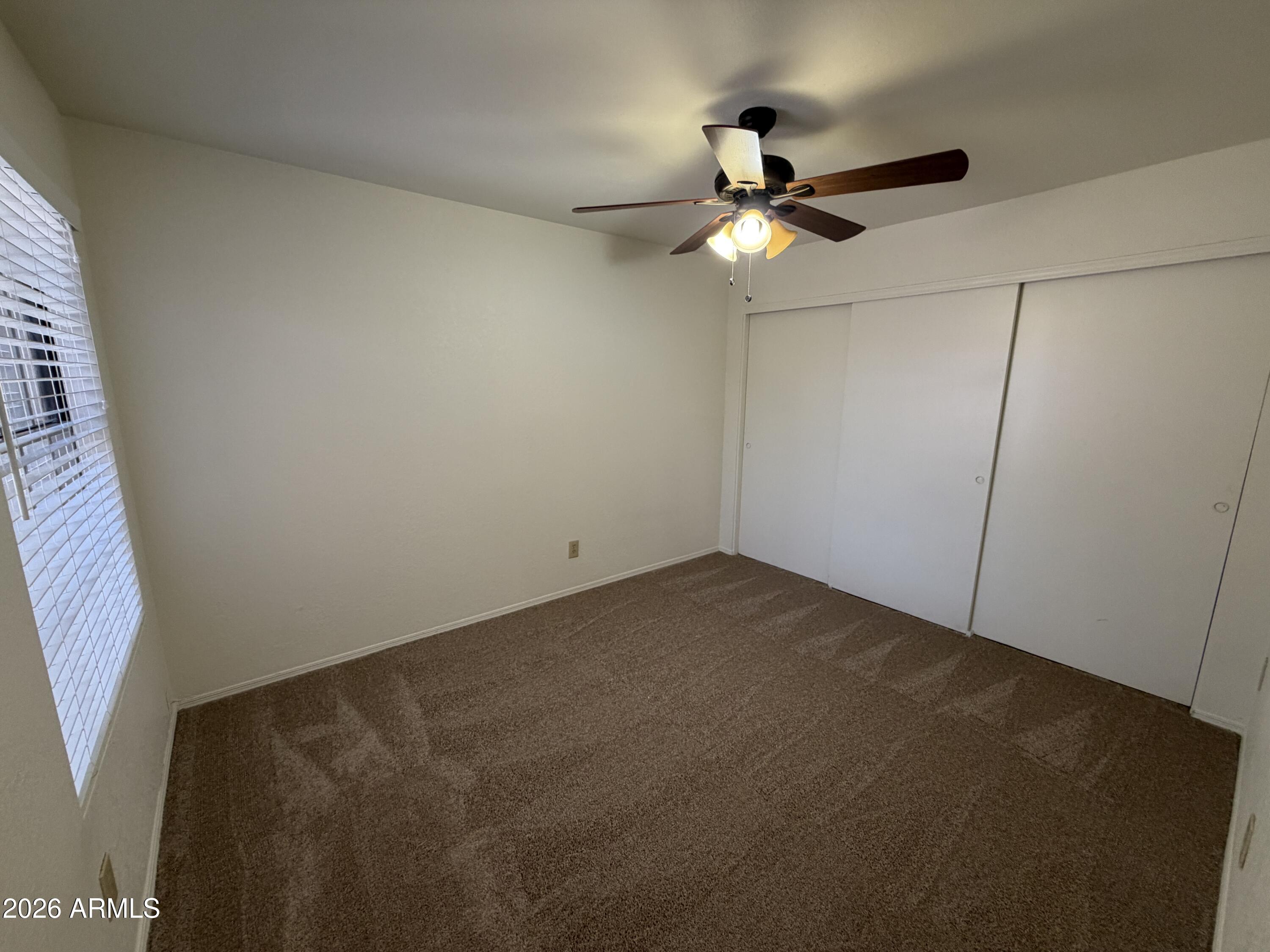 4263 East Agave Road Phoenix, AZ 85044 - Photo 18 of 21 an empty room with a window and a ceiling fan