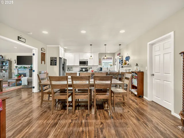 a kitchen with stainless steel appliances a dining table chairs and wooden floor