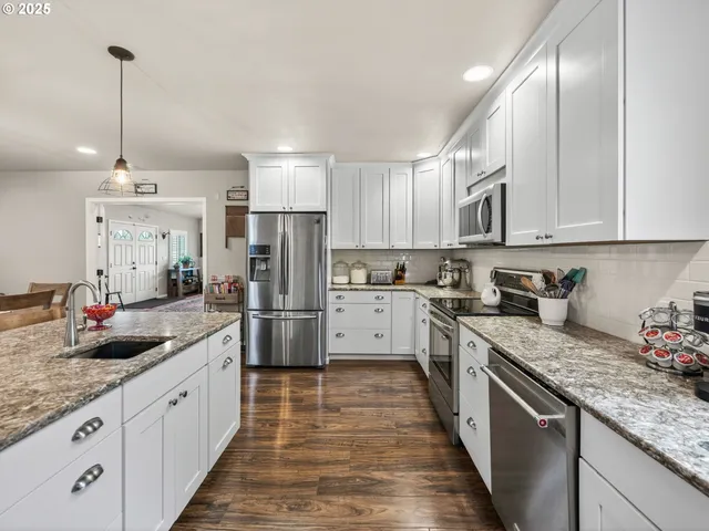 a kitchen with stainless steel appliances granite countertop a sink a stove and a refrigerator