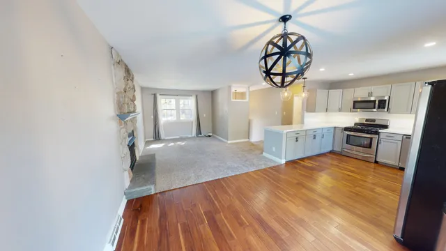 a kitchen with stainless steel appliances granite countertop a stove top oven a sink dishwasher and white cabinets with wooden floor