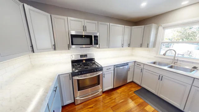 a kitchen with stainless steel appliances a sink a stove a microwave and cabinets