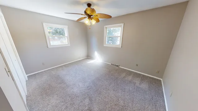 an empty room with windows and a chandelier fan