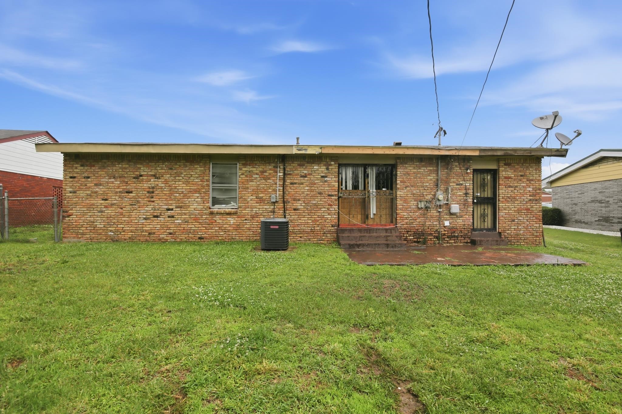 645 Parkrose Road Memphis, TN 38109 - Photo 5 of 32 Expansive grassy yard with a full brick exterior featuring a patio area, two entryways, and an outdoor HVAC unit