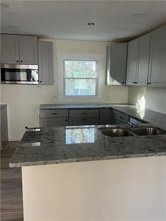 a kitchen with granite countertop a sink a stove and cabinets