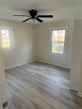 a view of an empty room with wooden floor and a window