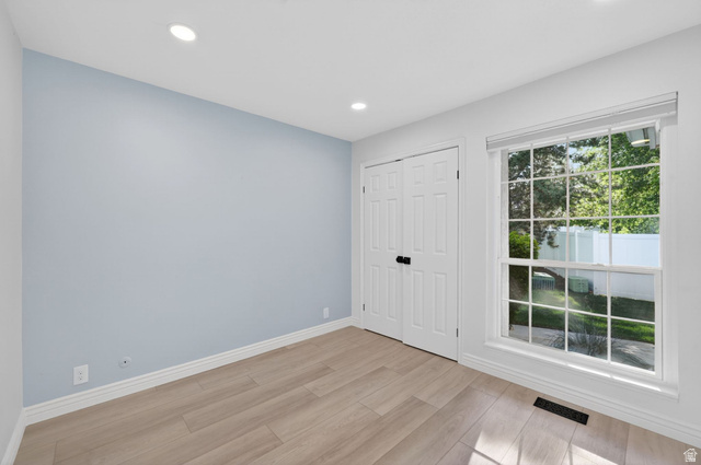 6969 South 855 East Midvale, UT 84047 - Photo 29 of 55 Bright room featuring wood-finish flooring, recessed lighting, double bi-fold doors with black hardware, white trim throughout, and a large window providing views of exterior greenery