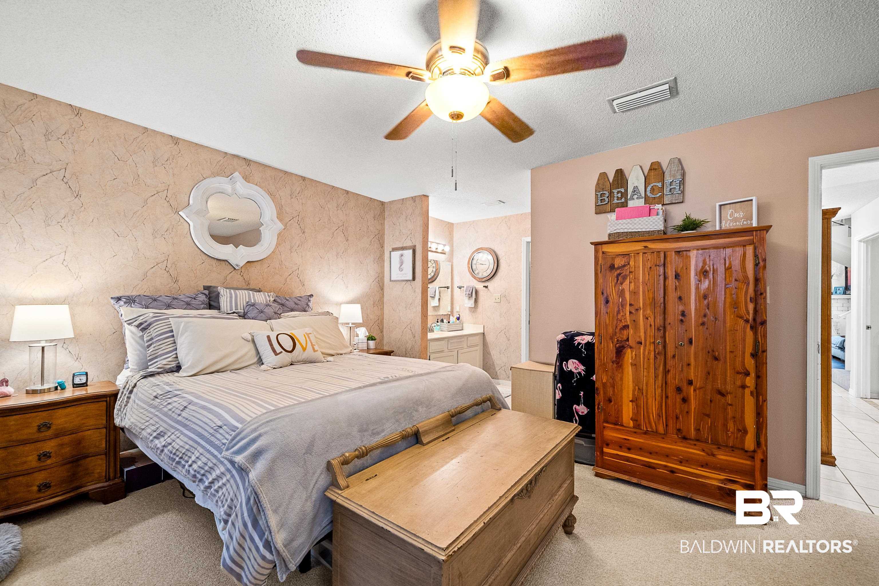 1701 Regency Road, Unit 106 Gulf Shores, AL 36542 - Photo 8 of 42 Bedroom with light colored carpet, a textured ceiling, ceiling fan, and ensuite bathroom