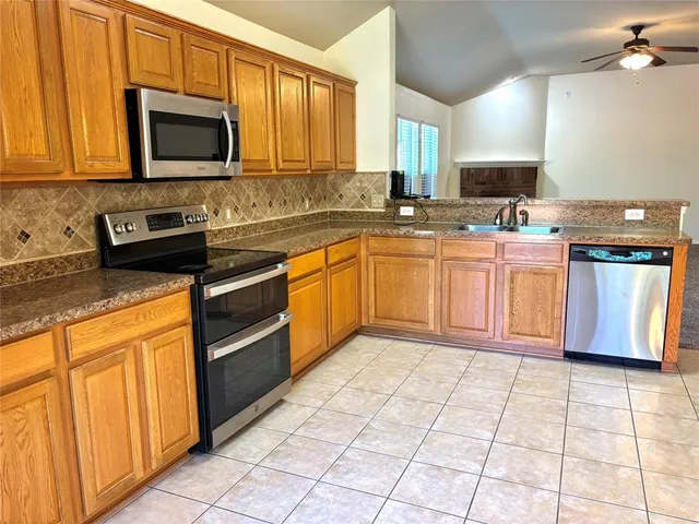 a kitchen with stainless steel appliances granite countertop a stove a sink and a microwave