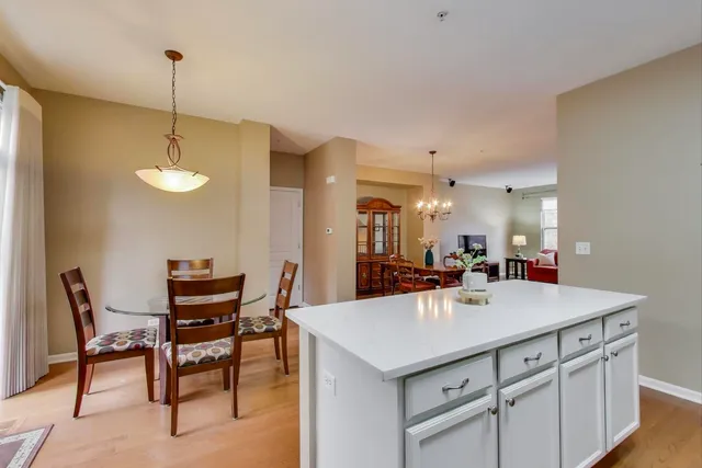a view of a kitchen counter space dining table chairs and white cabinets