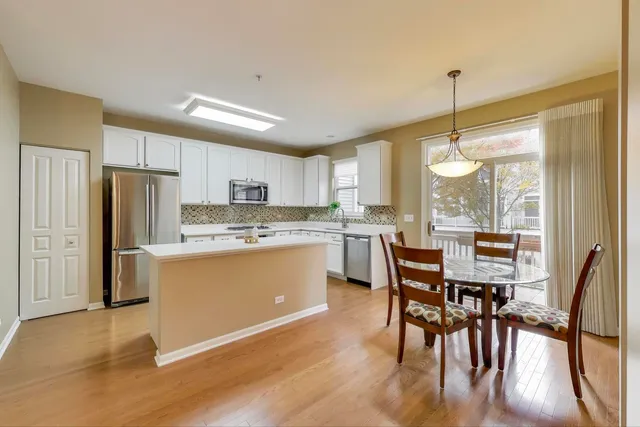 a kitchen with stainless steel appliances granite countertop a refrigerator a stove a kitchen island with a dining table and chairs