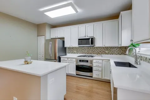 a kitchen with stainless steel appliances a stove refrigerator sink and cabinets