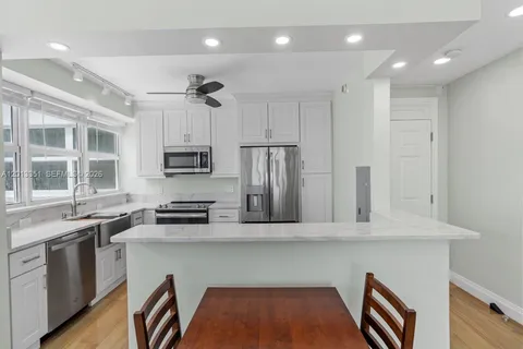 a kitchen with stainless steel appliances granite countertop a sink a stove a refrigerator cabinets and a dining table