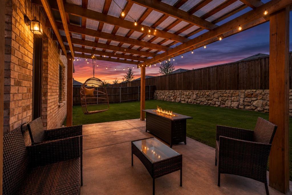 14065 Ilderton Street Pilot Point, TX 76258 - Photo 18 of 19 14065 Ilsderton St., Pilot Point Tx Expansive concrete patio featuring a wood pergola with string lights, brick exterior, and a stone retaining wall