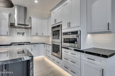 a large kitchen with stainless steel appliances kitchen island granite countertop a sink a stove and cabinets