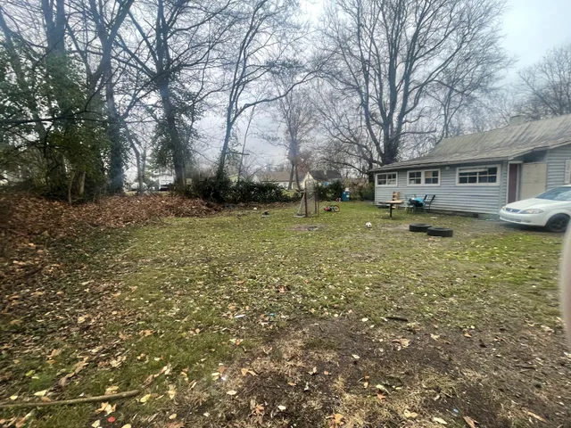 a backyard of a house with large trees and outdoor seating