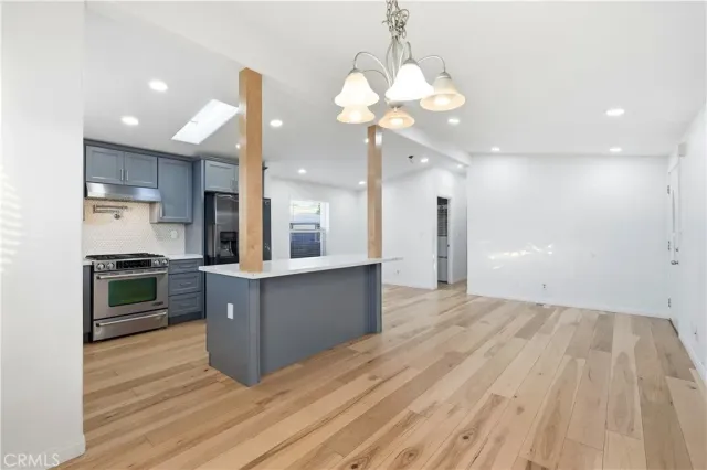 a kitchen with stainless steel appliances kitchen island granite countertop a stove a refrigerator a sink a oven with a dining table and chairs