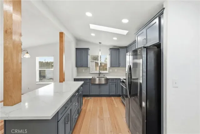 a large kitchen with kitchen island a large window cabinets a sink and stainless steel appliances