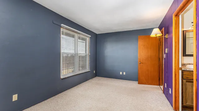 a view of an empty room with a window and bathroom