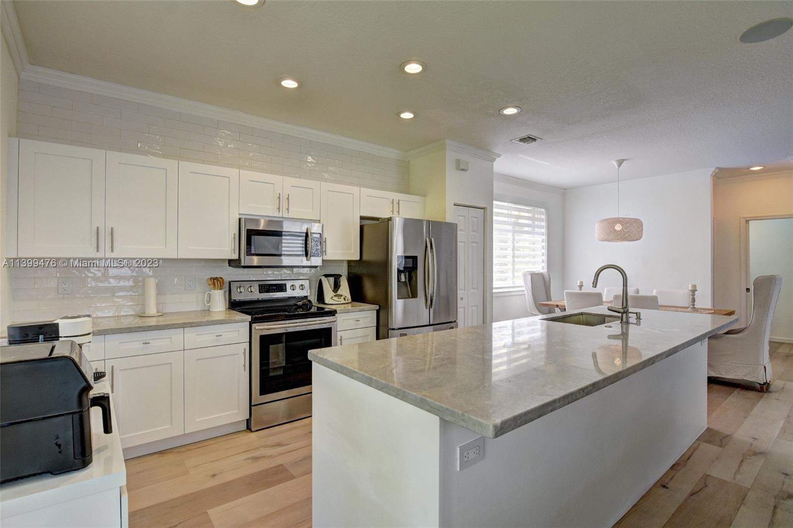 471 Fishtail Terrace Weston, FL 33327 - Photo 12 of 33 a kitchen with stainless steel appliances granite countertop a sink dishwasher a refrigerator and white cabinets with wooden floor