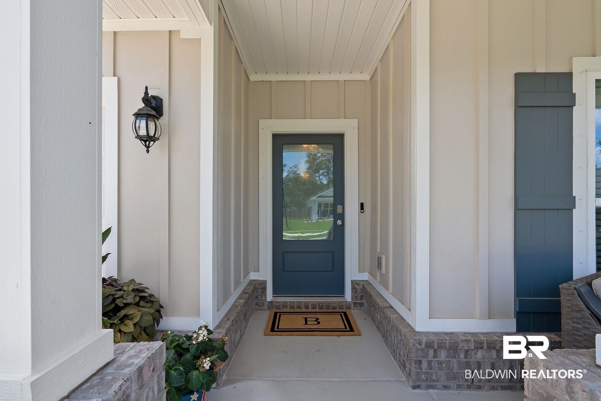 13966 Antler Hl Road Daphne, AL 36527 - Photo 2 of 44 Inviting entry featuring a glass-paneled front door, board and batten siding, brick foundation accents, a decorative exterior light fixture, and a white beadboard ceiling