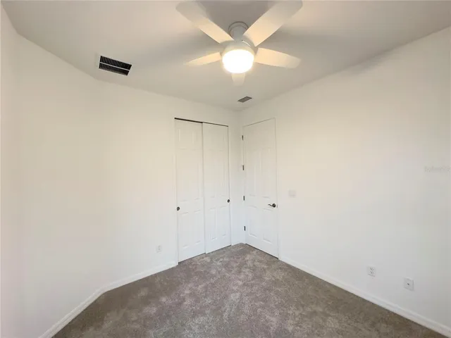an empty room with a ceiling fan and a window