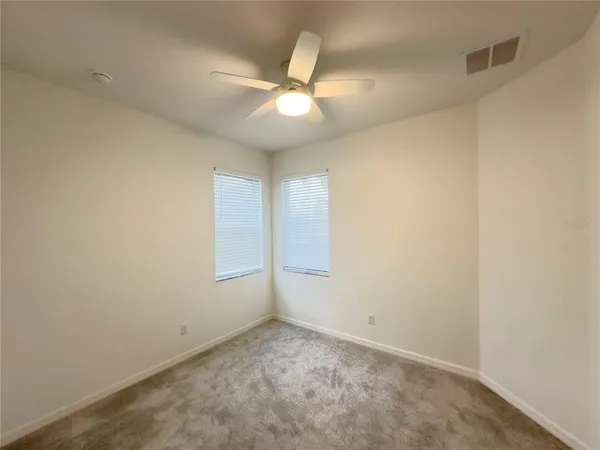 an empty room with a ceiling fan and a window