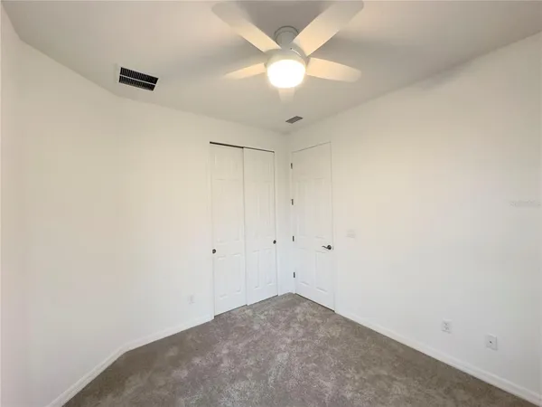 an empty room with a ceiling fan and a window