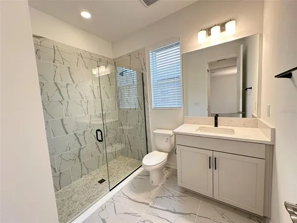 a bathroom with a granite countertop sink toilet and shower