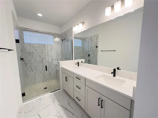 a spacious bathroom with double sink shower and a mirror
