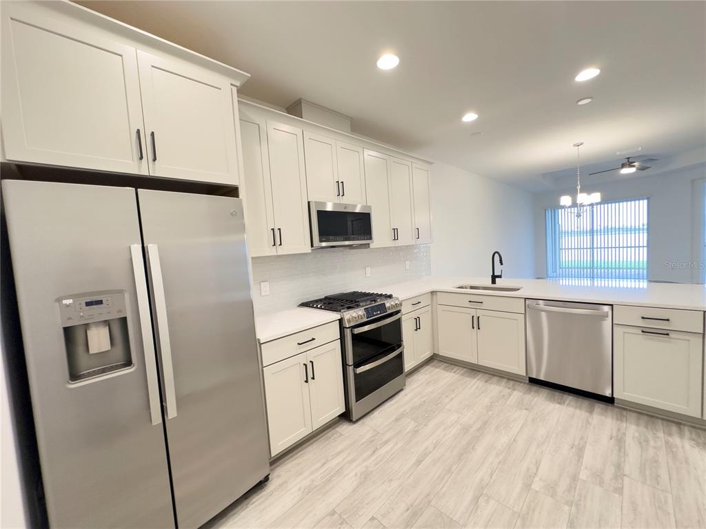 17937 Cherished Loop Lakewood Ranch, FL 34211 - Photo 6 of 30 a kitchen with a refrigerator a sink and white cabinets