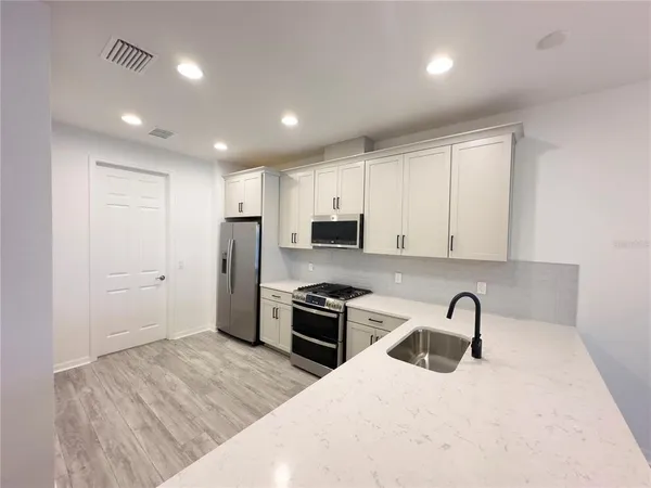a kitchen with granite countertop a stove a sink and a refrigerator