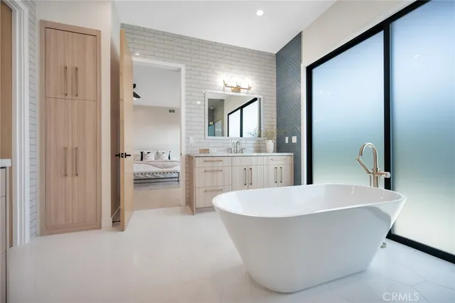 a white bath tub sitting in a room with a cabinet and a bookshelf